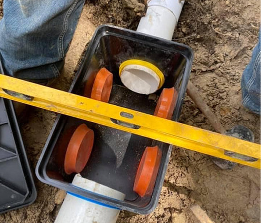 Technician repairing septic system components including baffles and risers